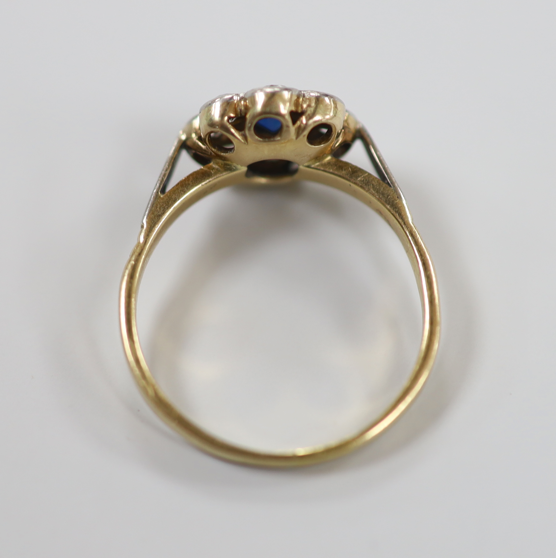 A 1940's yellow metal and plat, sapphire and diamond set circular cluster ring, size O, gross weight 3.8 grams.